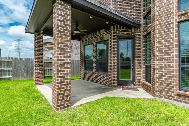 property entrance with a lawn, ceiling fan, and a patio area