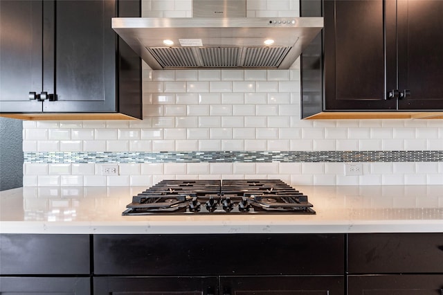 kitchen featuring wall chimney exhaust hood, dark brown cabinets, black gas cooktop, and tasteful backsplash