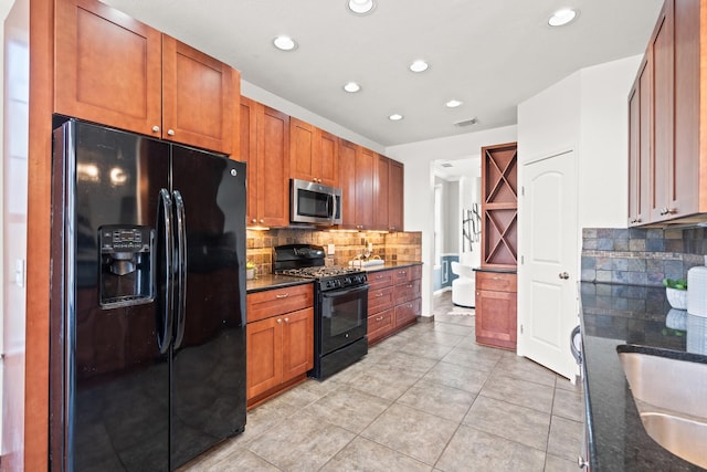 kitchen with dark stone counters, black appliances, sink, light tile patterned floors, and tasteful backsplash