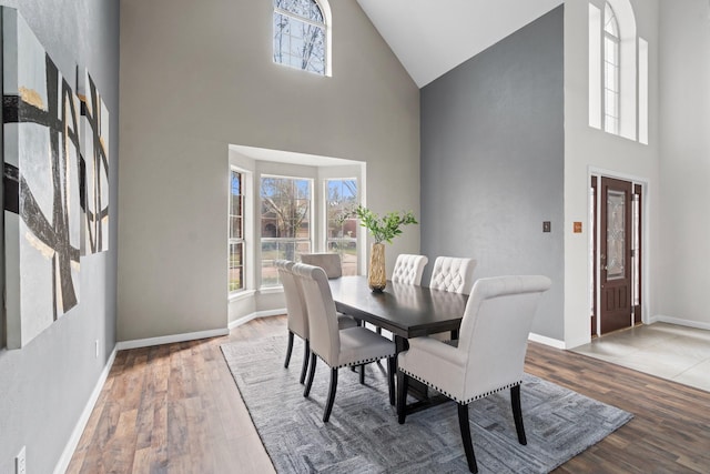 dining space with a towering ceiling and hardwood / wood-style flooring