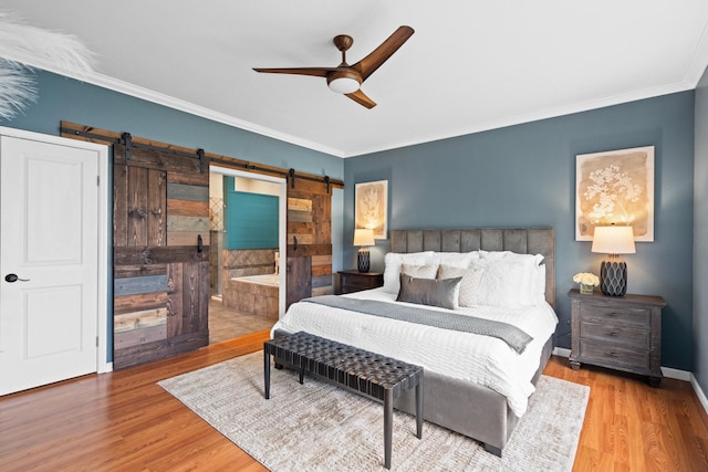 bedroom with ornamental molding, ceiling fan, a barn door, hardwood / wood-style flooring, and connected bathroom