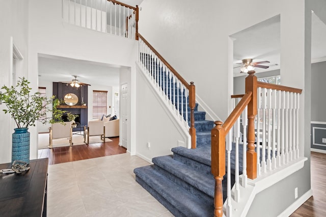 stairway with tile patterned flooring, a towering ceiling, and ceiling fan