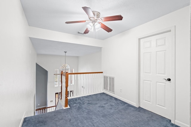 empty room with ceiling fan with notable chandelier and dark colored carpet