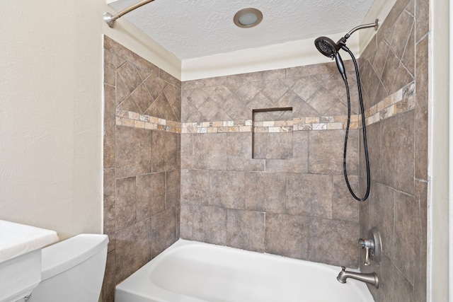 bathroom featuring a textured ceiling, tiled shower / bath combo, and toilet