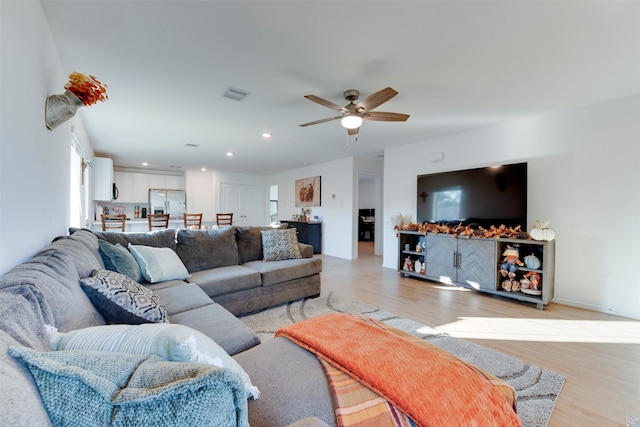 living room with ceiling fan and light wood-type flooring