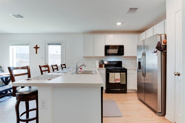 kitchen featuring a breakfast bar area, sink, white cabinets, and black appliances