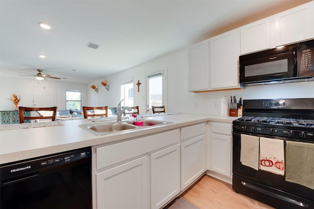 kitchen with kitchen peninsula, white cabinetry, sink, and black appliances