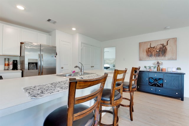 kitchen featuring white cabinets, stainless steel fridge with ice dispenser, light hardwood / wood-style flooring, and sink