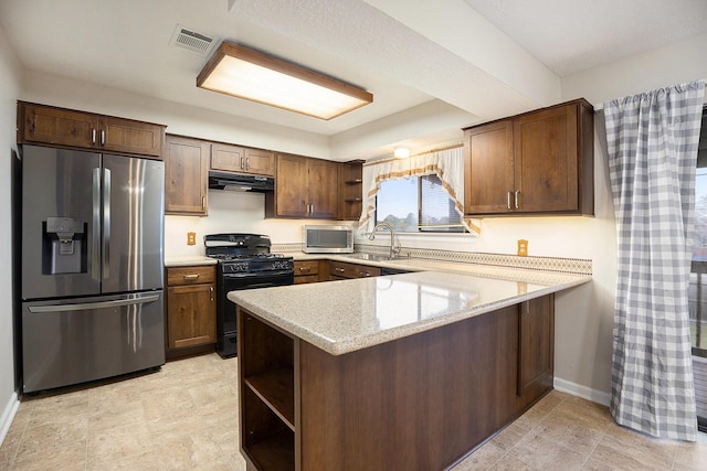 kitchen with light stone countertops, sink, kitchen peninsula, dark brown cabinets, and appliances with stainless steel finishes