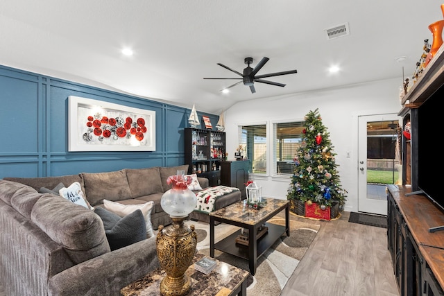 living room with ceiling fan, light hardwood / wood-style floors, bar, and vaulted ceiling