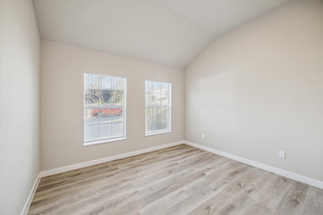 spare room featuring light hardwood / wood-style flooring and lofted ceiling