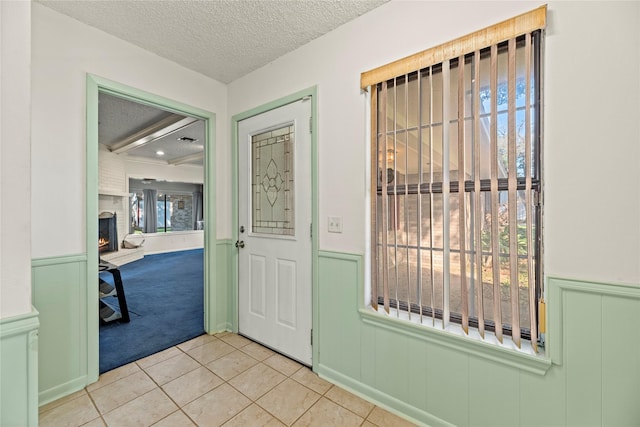 tiled foyer with a fireplace and a textured ceiling