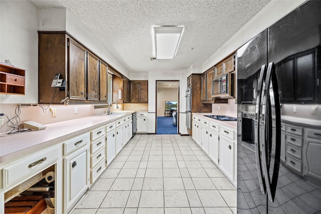 kitchen featuring white cabinets, double wall oven, sink, a textured ceiling, and black fridge with ice dispenser