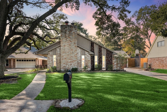 view of front of home with a lawn, central AC unit, and a garage