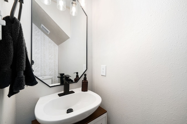 bathroom featuring visible vents, a textured wall, and vanity