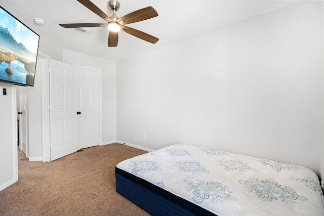 carpeted bedroom featuring a ceiling fan, visible vents, and baseboards