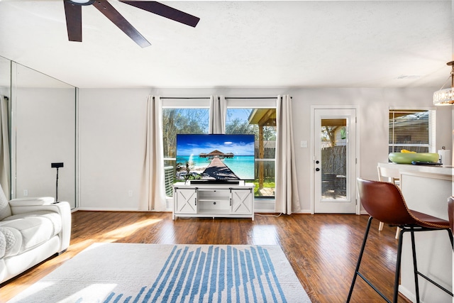 living room with plenty of natural light, ceiling fan, and dark wood-type flooring