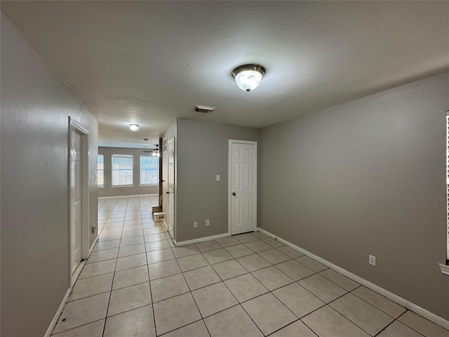 spare room with a textured ceiling, ceiling fan, and light tile patterned floors