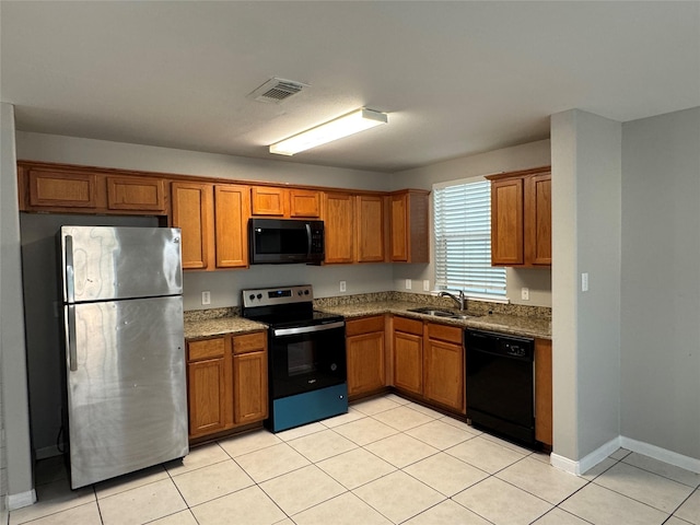 kitchen with light tile patterned flooring, dark stone countertops, black appliances, and sink