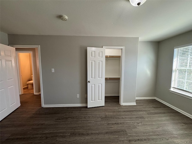 unfurnished bedroom with a walk in closet and dark hardwood / wood-style flooring