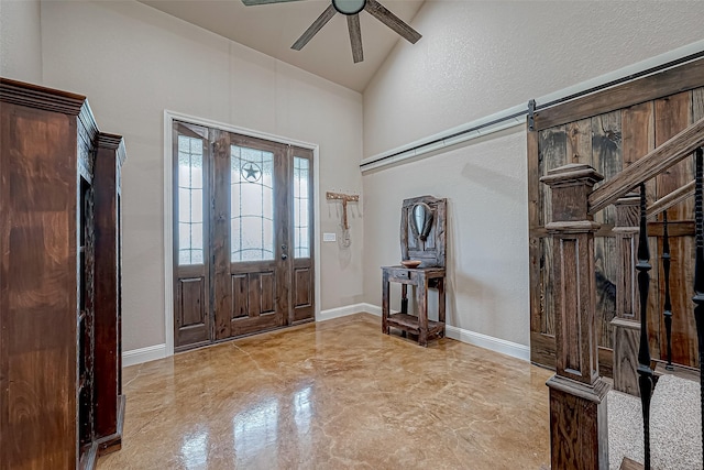 foyer entrance with a barn door, ceiling fan, and lofted ceiling