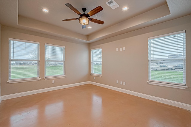 empty room featuring plenty of natural light, concrete floors, and a tray ceiling