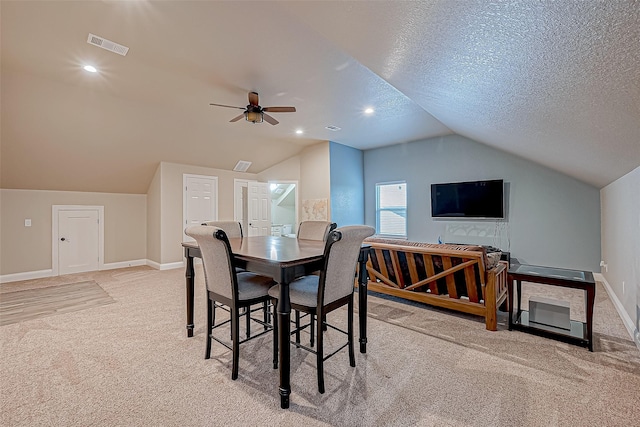 carpeted dining room with vaulted ceiling, ceiling fan, and a textured ceiling