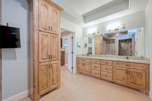 bathroom with a shower, vanity, and a textured ceiling