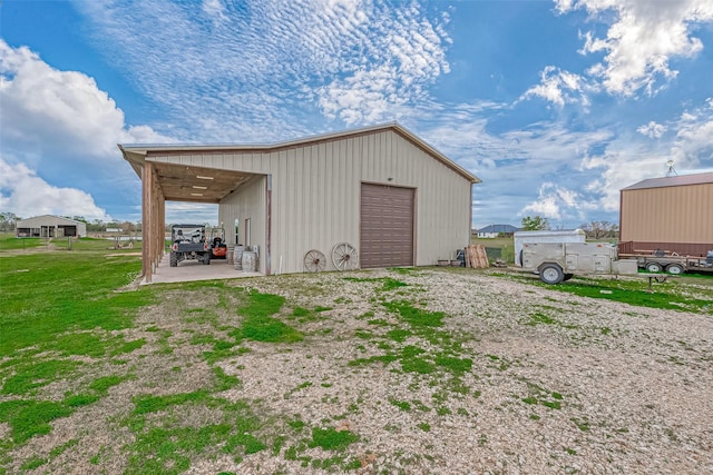 view of outdoor structure with a yard, a carport, and a garage