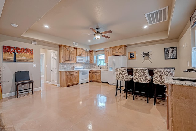 kitchen featuring sink, a raised ceiling, white appliances, and backsplash