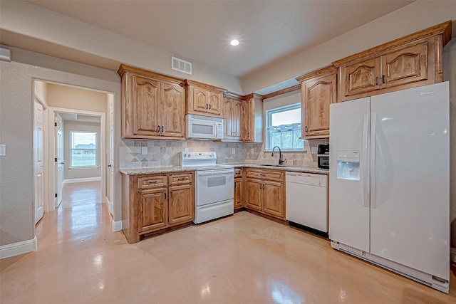 kitchen with decorative backsplash, white appliances, light stone counters, and sink