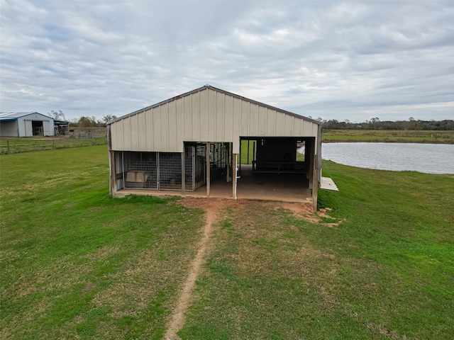 view of outbuilding with a lawn and a water view