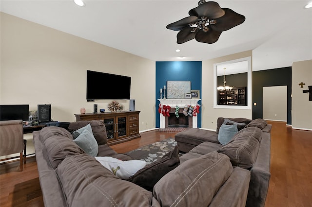 living room featuring a fireplace, ceiling fan with notable chandelier, and dark hardwood / wood-style floors