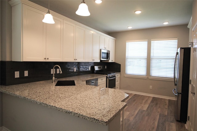 kitchen with white cabinetry, light stone counters, kitchen peninsula, decorative light fixtures, and appliances with stainless steel finishes