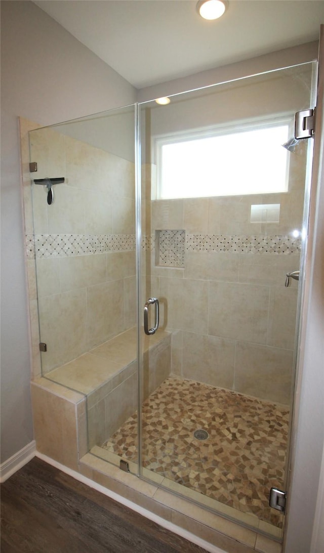 bathroom with hardwood / wood-style flooring and a shower with shower door