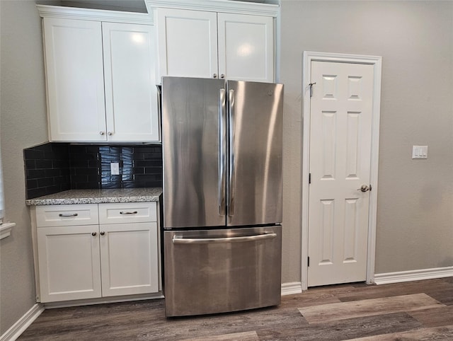 kitchen featuring backsplash, light stone counters, dark hardwood / wood-style flooring, white cabinetry, and stainless steel refrigerator