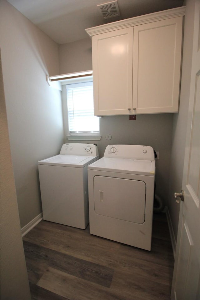 washroom featuring washing machine and clothes dryer, dark wood-type flooring, and cabinets