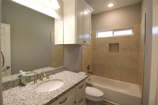 full bathroom featuring vanity, tiled shower / bath combo, and toilet