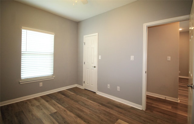 empty room with ceiling fan and dark hardwood / wood-style flooring