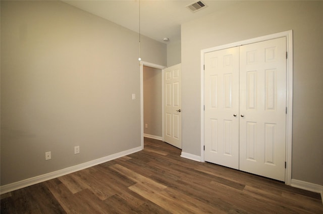 unfurnished bedroom featuring a closet and dark wood-type flooring