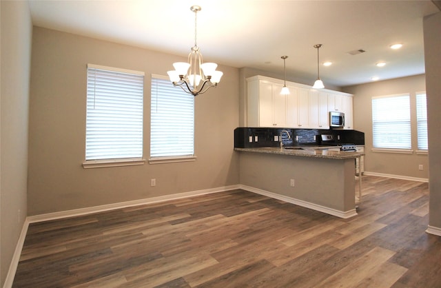 kitchen featuring kitchen peninsula, stone countertops, dark hardwood / wood-style floors, white cabinetry, and hanging light fixtures