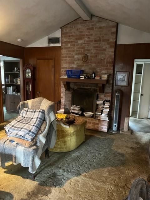 carpeted living room with a fireplace, vaulted ceiling with beams, and wooden walls