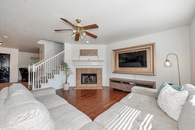 living room with ceiling fan, dark hardwood / wood-style flooring, and a tile fireplace