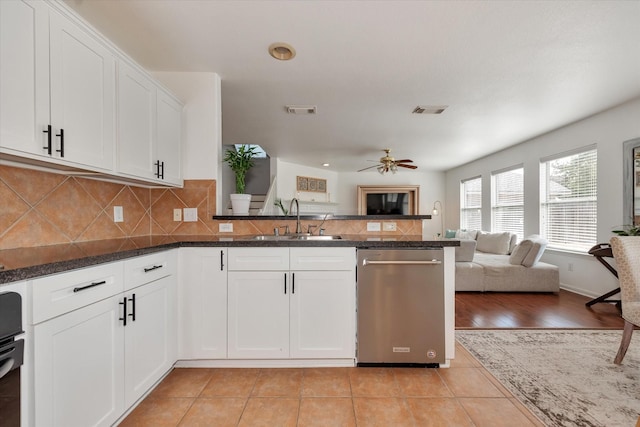 kitchen featuring dishwasher, sink, white cabinets, backsplash, and kitchen peninsula