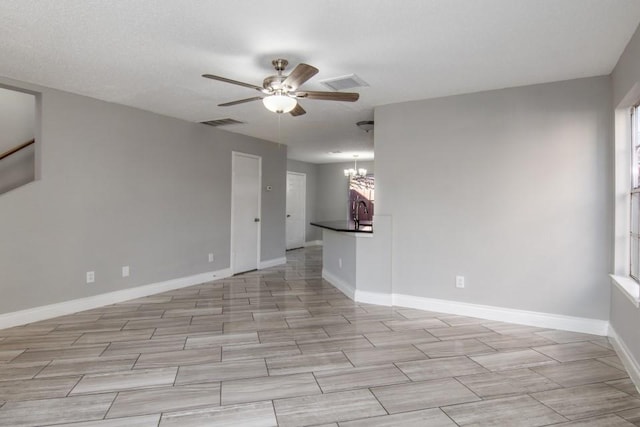 spare room with ceiling fan with notable chandelier