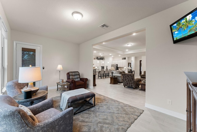 tiled living room featuring a textured ceiling and a tray ceiling