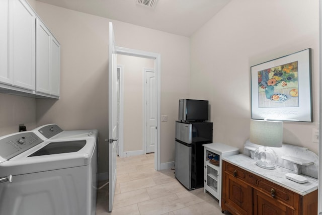 laundry room with washer and dryer, light tile patterned floors, and cabinets