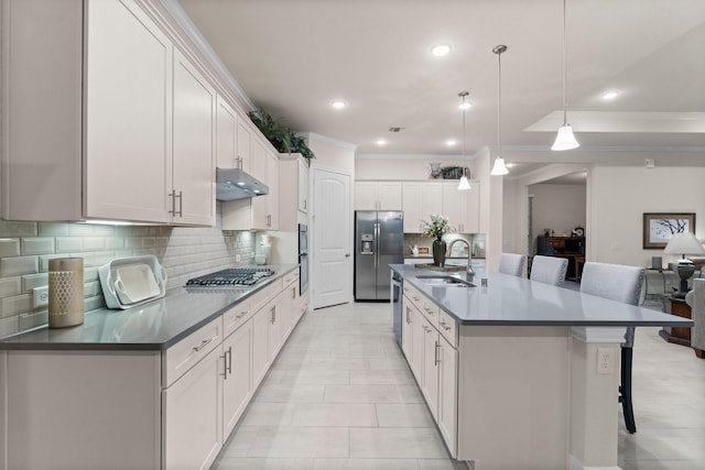 kitchen featuring a kitchen island with sink, white cabinets, decorative light fixtures, and appliances with stainless steel finishes