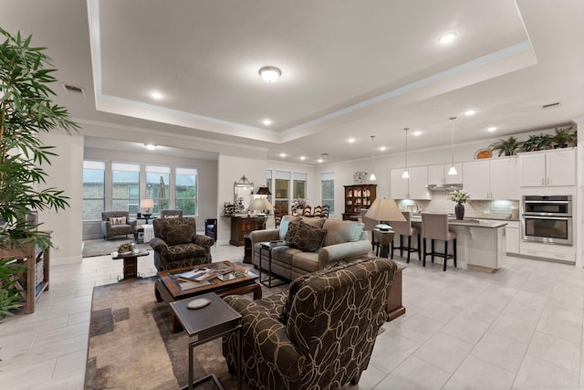 tiled living room featuring a raised ceiling and ornamental molding