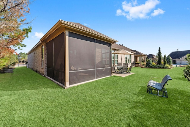 rear view of property featuring a lawn, a patio area, and a sunroom